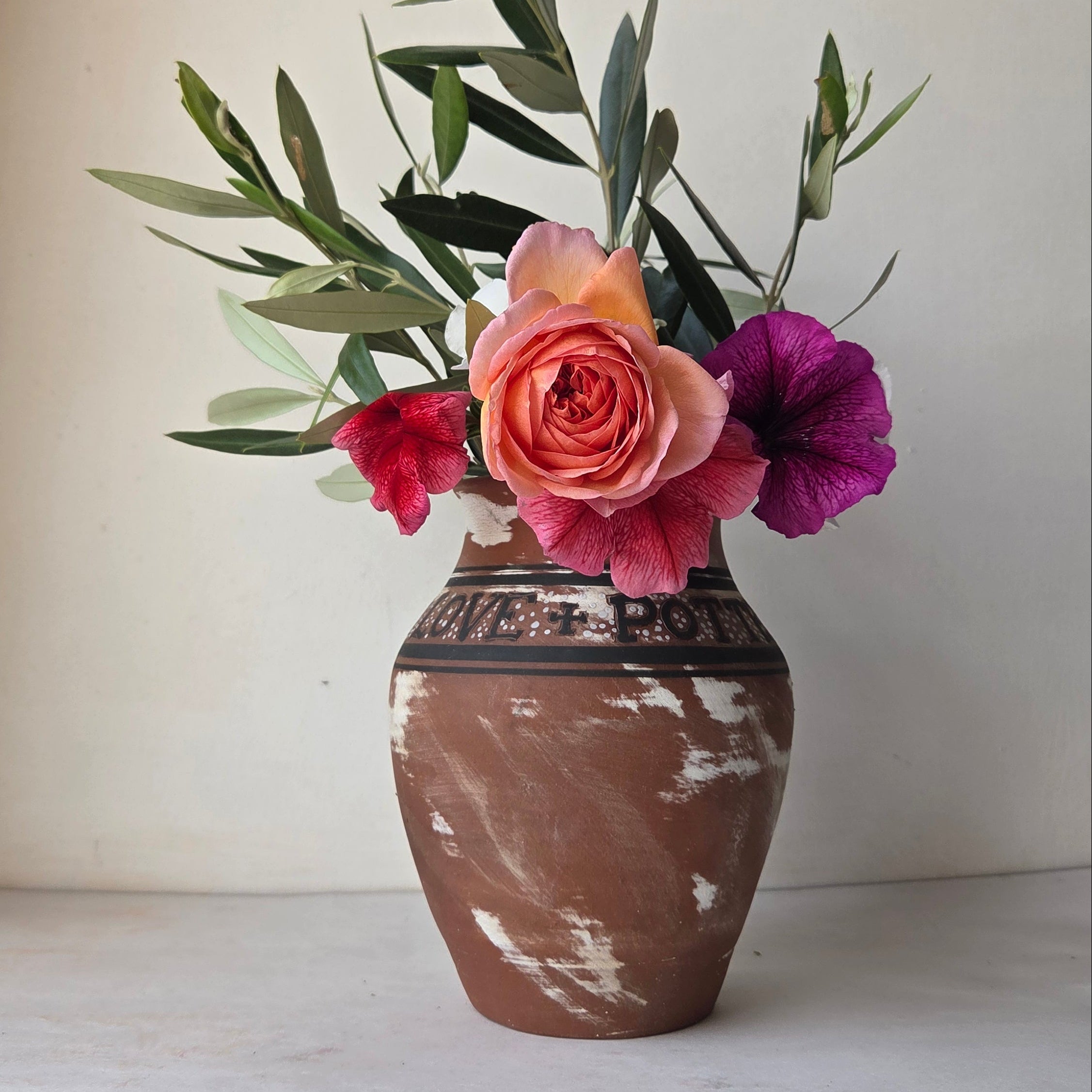 Floral arrangement in a rustic wooden vase against a plain wall