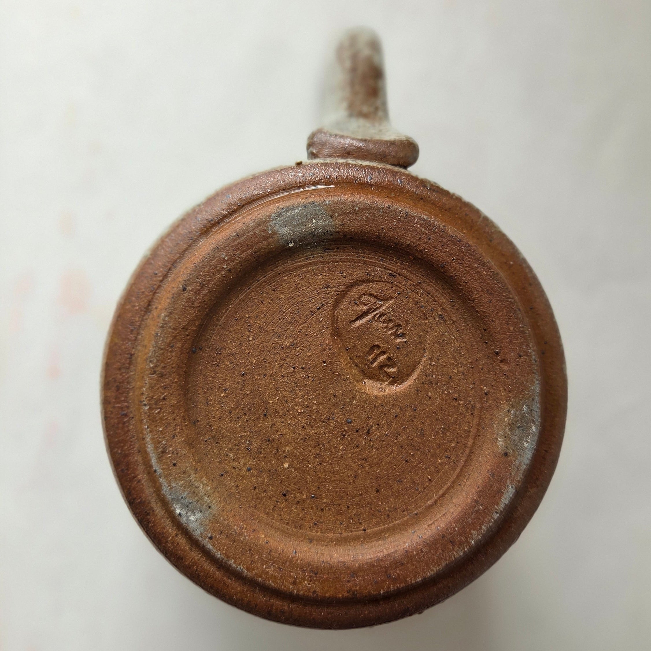 Close-up of bottom of ceramic mug on a light background